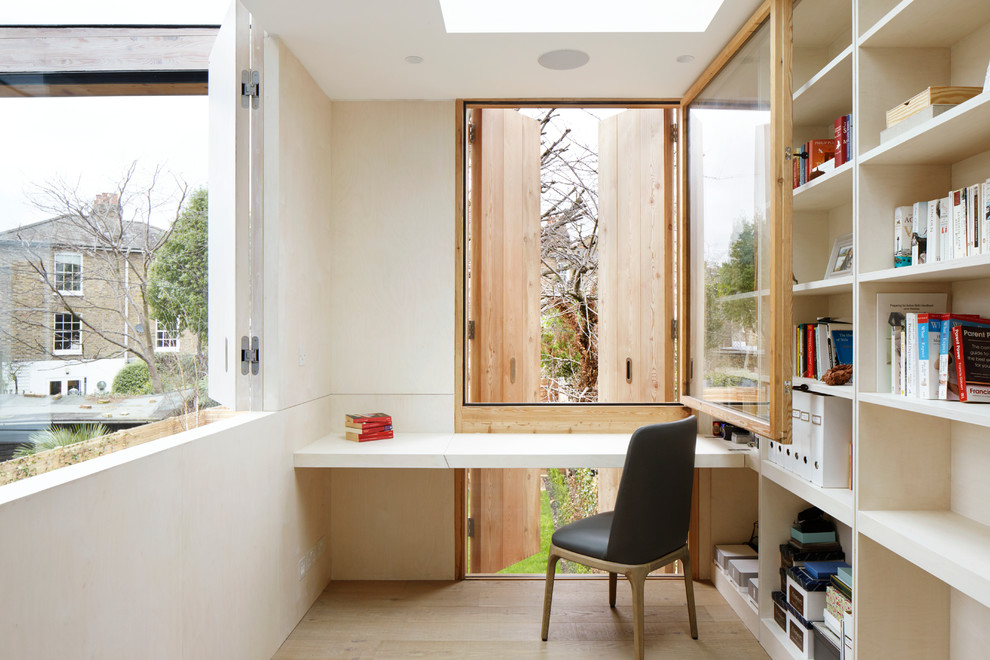 Exempel på ett litet modernt arbetsrum, med ett bibliotek, vita väggar, ljust trägolv, ett inbyggt skrivbord och beiget golv
