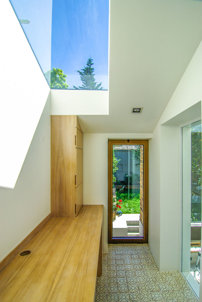 На фото: маленькое рабочее место в стиле модернизм с белыми стенами, полом из керамической плитки и встроенным рабочим столом для на участке и в саду