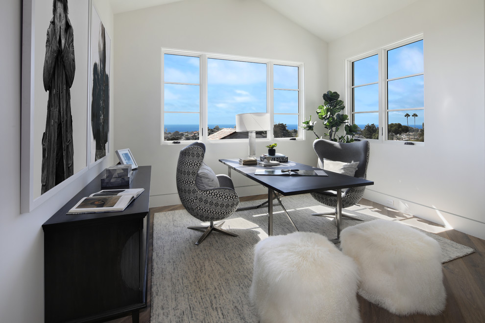 Imagen de despacho actual con paredes blancas, suelo de madera en tonos medios, escritorio independiente y suelo marrón