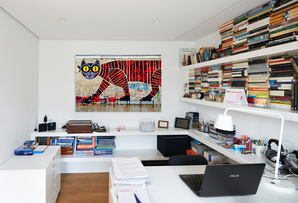 Ejemplo de despacho bohemio de tamaño medio sin chimenea con suelo de madera clara, escritorio empotrado y paredes blancas