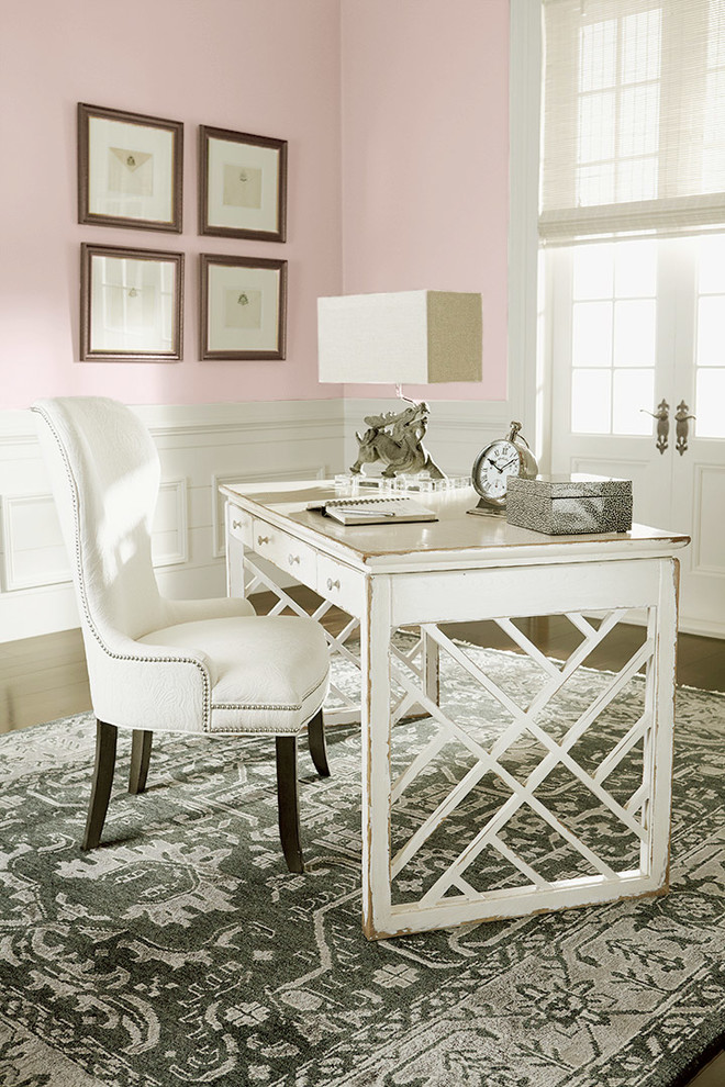 Foto på ett eklektiskt arbetsrum, med rosa väggar, mörkt trägolv och ett fristående skrivbord