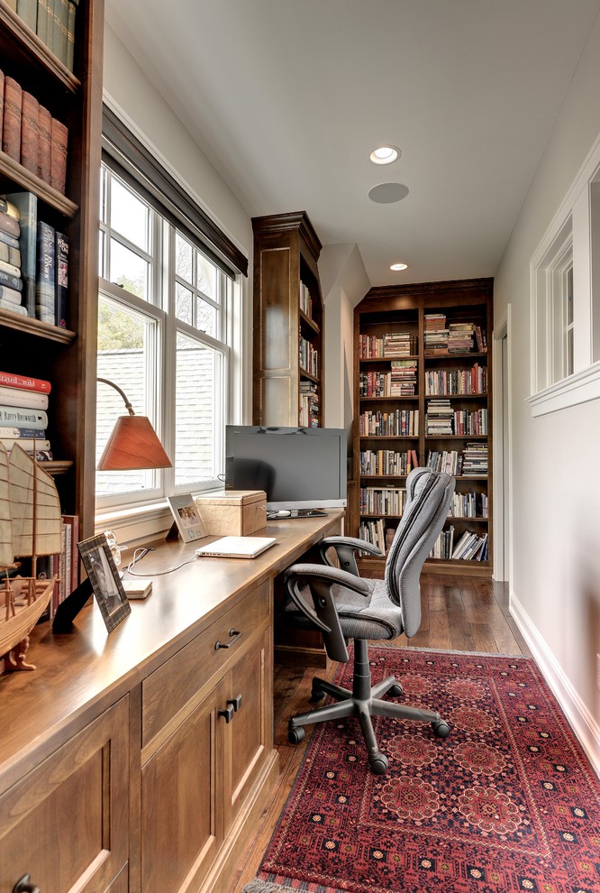 Modelo de despacho tradicional sin chimenea con paredes grises, suelo de madera oscura y escritorio empotrado
