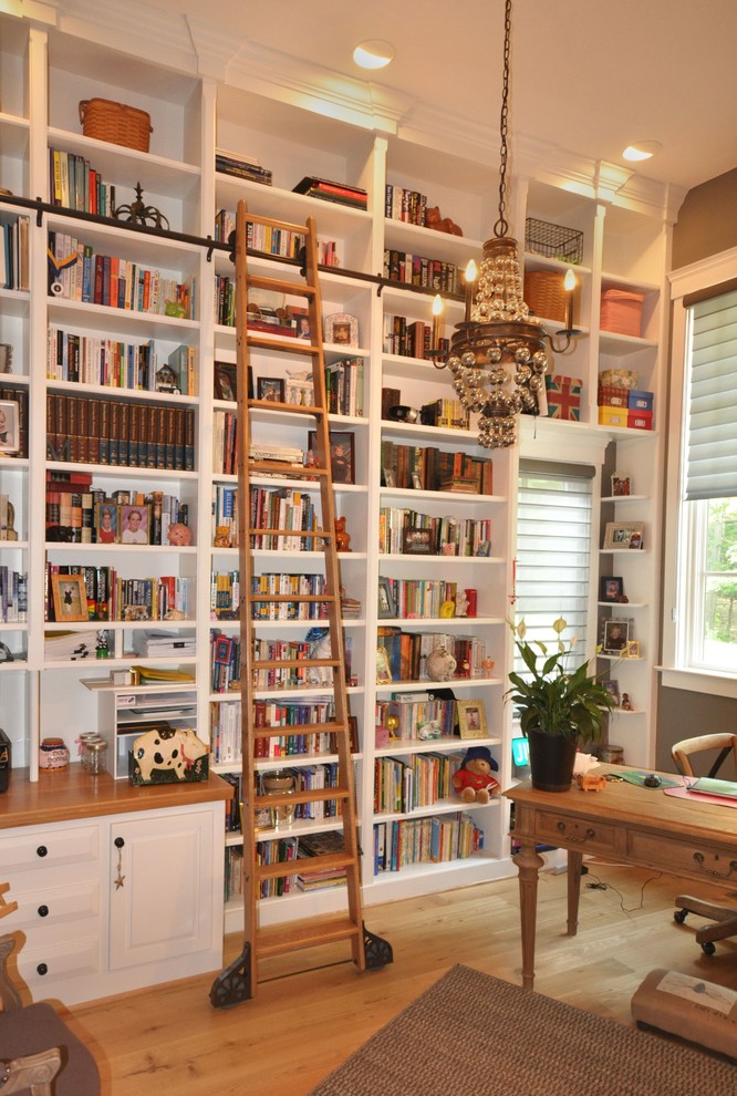 Exempel på ett stort klassiskt arbetsrum, med ett bibliotek, bruna väggar, ljust trägolv, ett inbyggt skrivbord och beiget golv