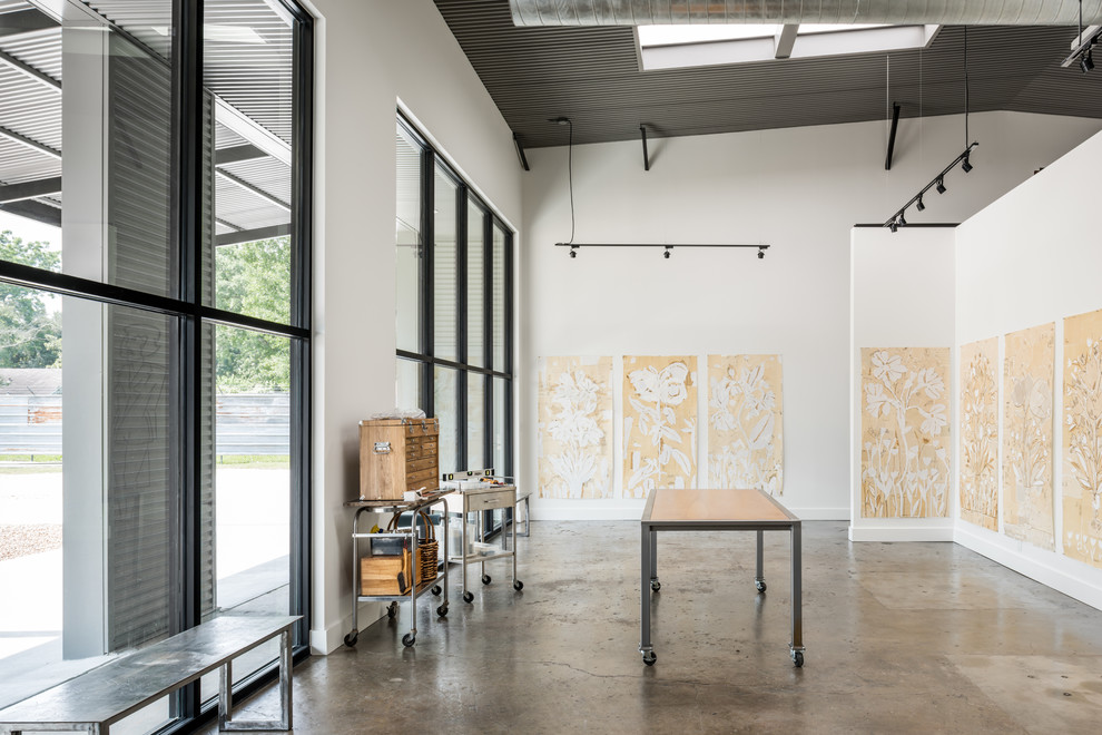 Großes Industrial Arbeitszimmer mit Studio, weißer Wandfarbe und Betonboden in Houston