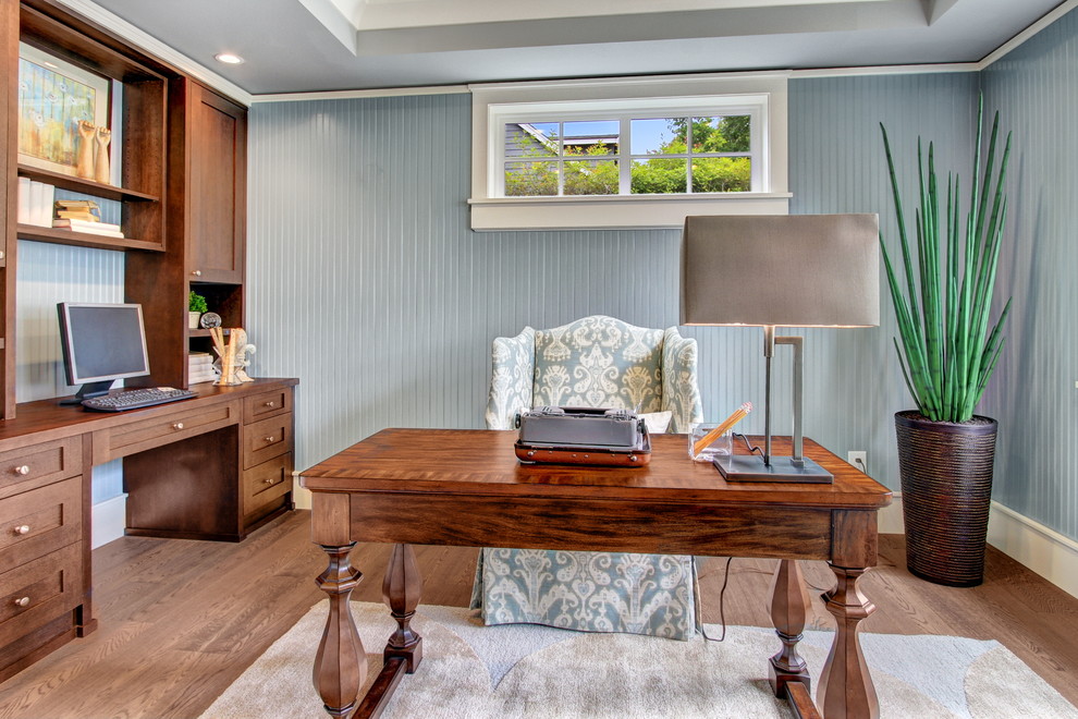 Ejemplo de despacho clásico con suelo de madera oscura, escritorio independiente y paredes azules
