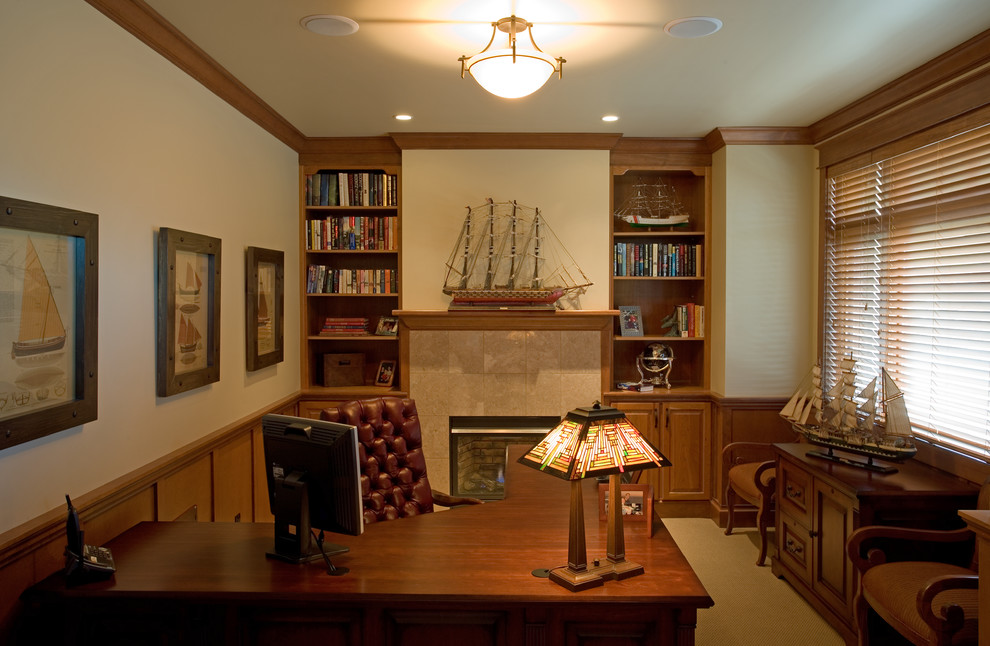 Cette image montre un bureau craftsman de taille moyenne avec un mur beige, moquette, une cheminée standard, un manteau de cheminée en pierre et un bureau indépendant.