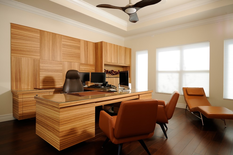 На фото: большой кабинет в современном стиле с встроенным рабочим столом, бежевыми стенами, темным паркетным полом и коричневым полом