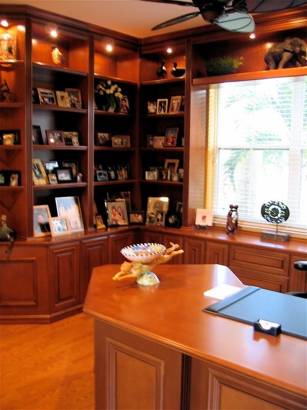 Example of a large classic built-in desk light wood floor and brown floor home office library design in Miami with beige walls