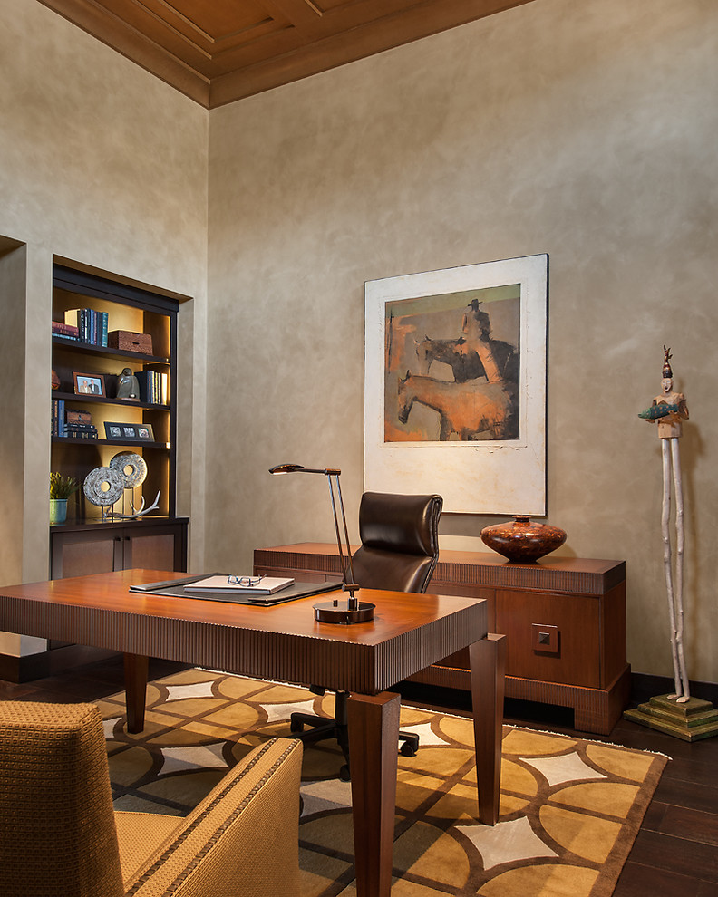 Diseño de despacho actual grande sin chimenea con paredes beige, suelo de madera oscura y escritorio independiente