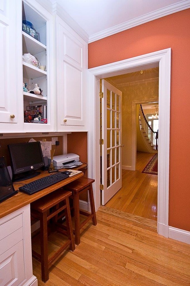 ボストンにある小さなトラディショナルスタイルのおしゃれなホームオフィス・書斎 (オレンジの壁、淡色無垢フローリング、造り付け机) の写真