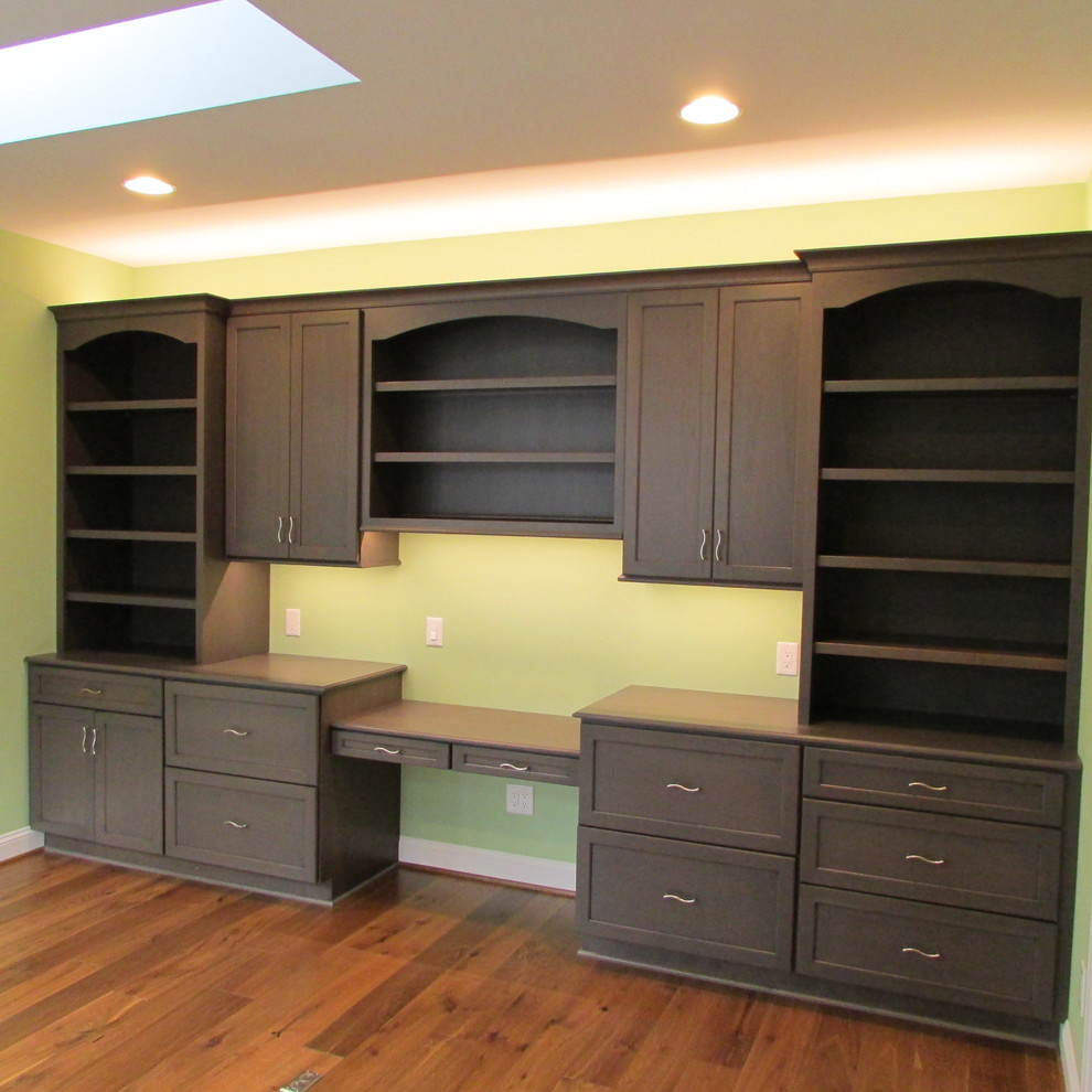 Ejemplo de despacho de estilo americano de tamaño medio con paredes verdes, suelo de madera en tonos medios, escritorio empotrado y suelo marrón