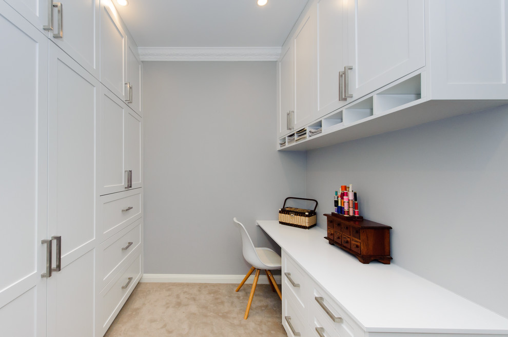 Modelo de sala de manualidades actual de tamaño medio con paredes blancas, escritorio empotrado y moqueta