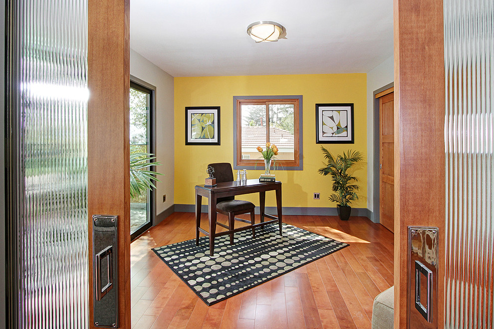На фото: кабинет в стиле ретро с желтыми стенами, паркетным полом среднего тона, отдельно стоящим рабочим столом и коричневым полом