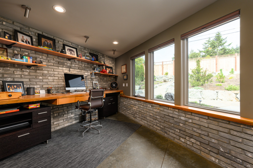 Foto de despacho industrial con paredes grises, suelo de cemento, escritorio empotrado y suelo gris