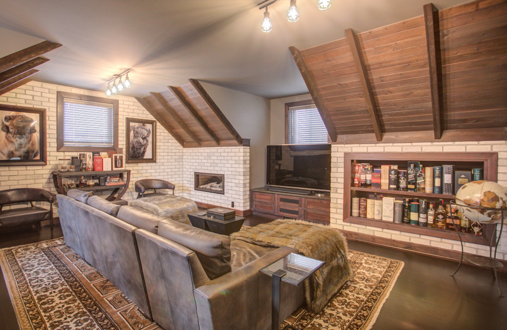 カルガリーにあるラグジュアリーな広いコンテンポラリースタイルのおしゃれな書斎 (グレーの壁、標準型暖炉、レンガの暖炉まわり、造り付け机、茶色い床) の写真