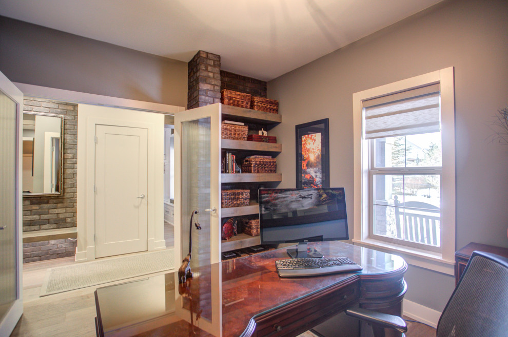 Cette image montre un grand bureau design avec un mur gris, parquet clair, un bureau indépendant et un sol marron.