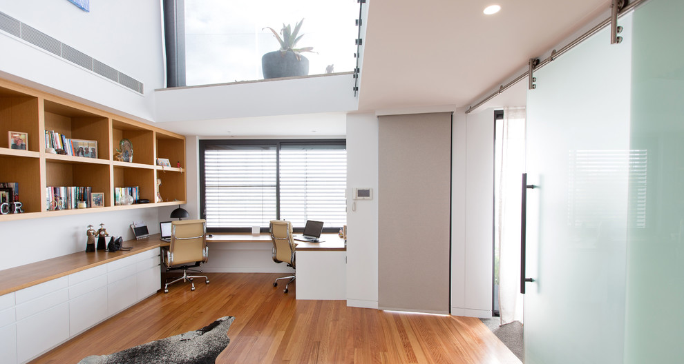 Exemple d'un grand bureau tendance avec un mur blanc, parquet clair, un bureau intégré et un sol beige.