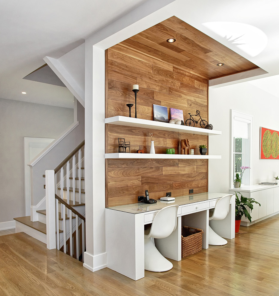 Contemporary study in New York with medium hardwood flooring and a built-in desk.
