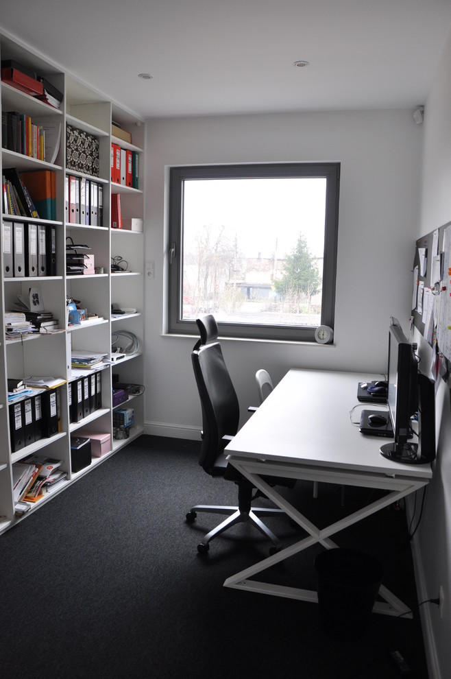 Foto di un piccolo atelier minimalista con pareti bianche, moquette e scrivania autoportante
