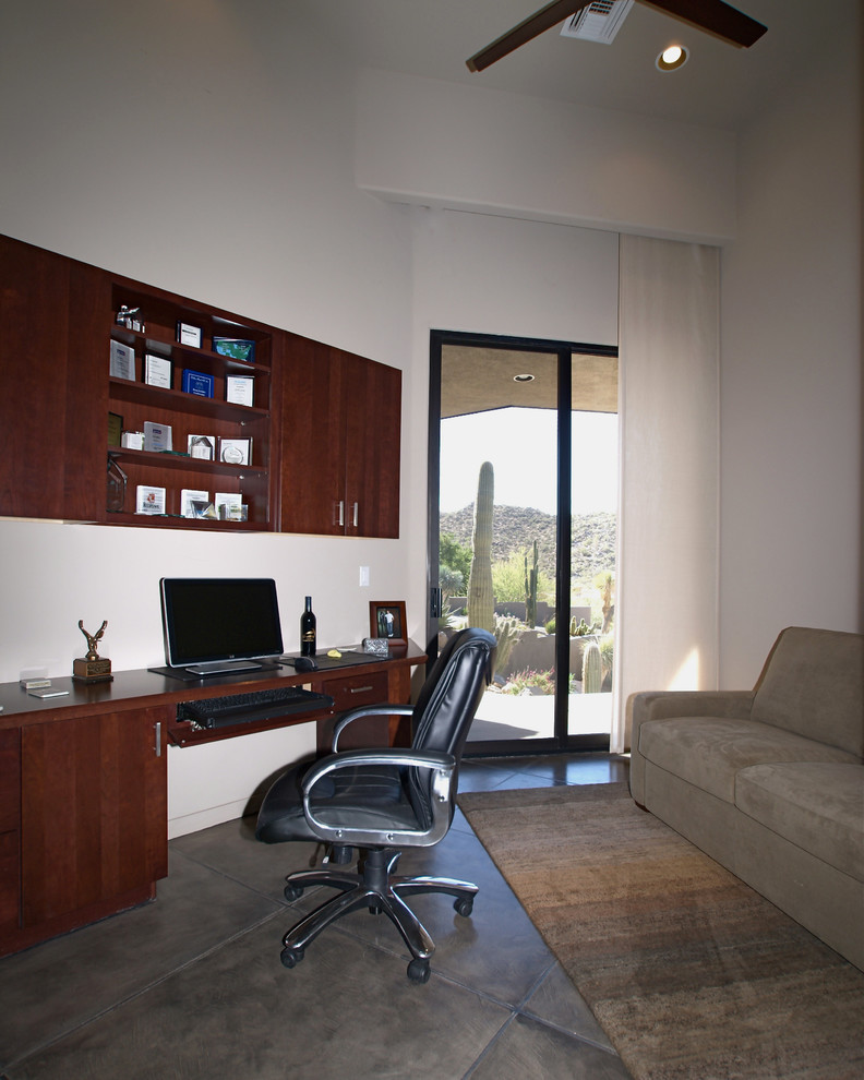 На фото: кабинет в современном стиле с бежевыми стенами, бетонным полом и встроенным рабочим столом с