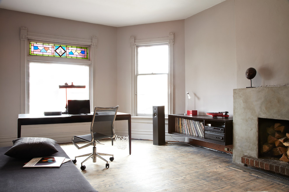 トロントにあるコンテンポラリースタイルのおしゃれなホームオフィス・書斎 (白い壁、無垢フローリング、標準型暖炉、コンクリートの暖炉まわり、自立型机) の写真