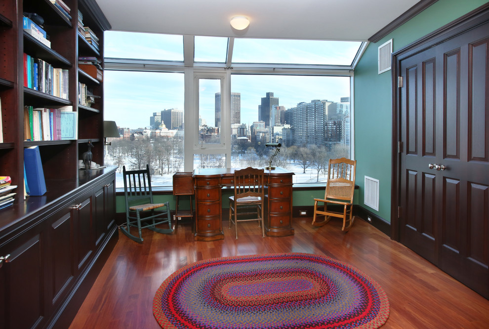 Cette photo montre un grand bureau chic avec un bureau indépendant, un mur vert et un sol en bois brun.