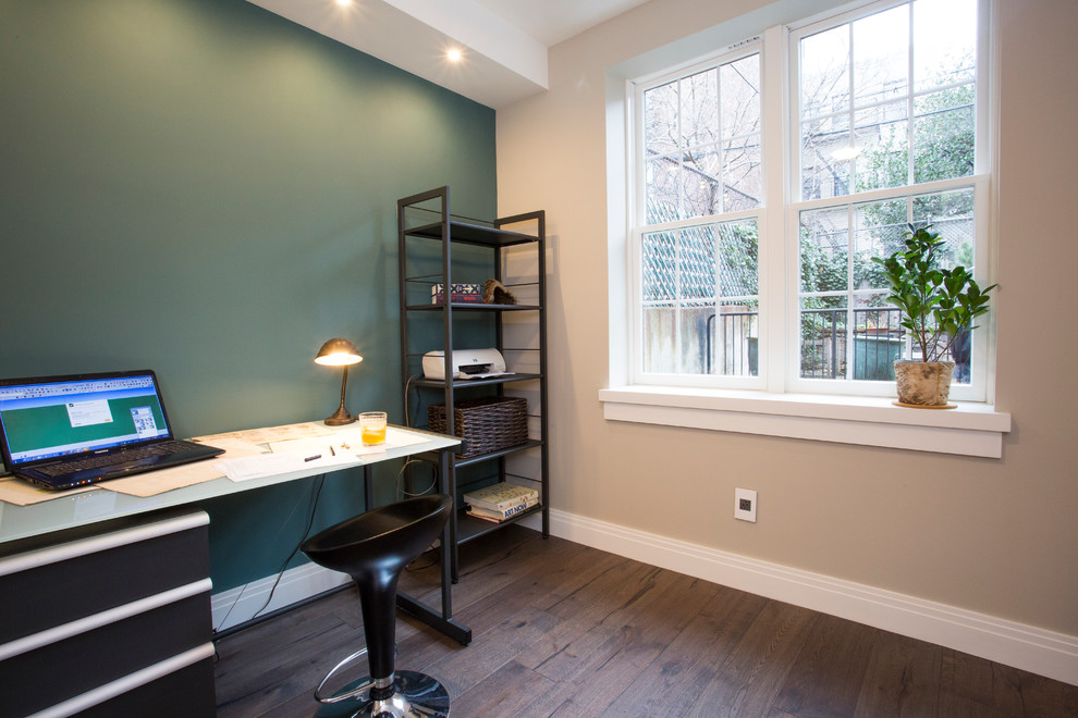 Modelo de despacho clásico renovado de tamaño medio con paredes verdes, suelo de madera oscura y escritorio independiente