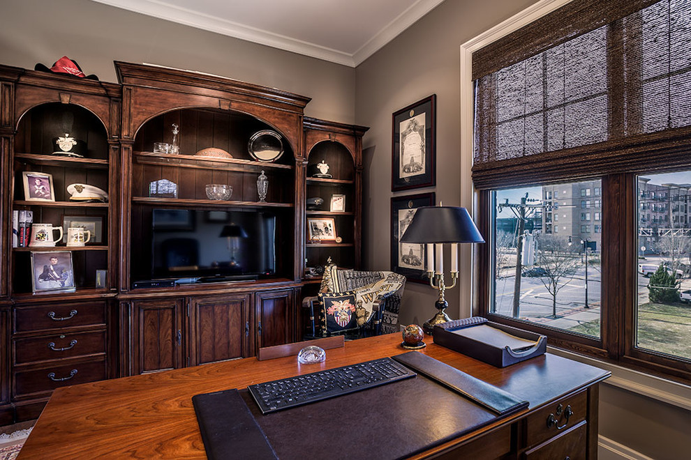 Großes Klassisches Arbeitszimmer ohne Kamin mit Arbeitsplatz, grauer Wandfarbe, dunklem Holzboden und freistehendem Schreibtisch in Sonstige