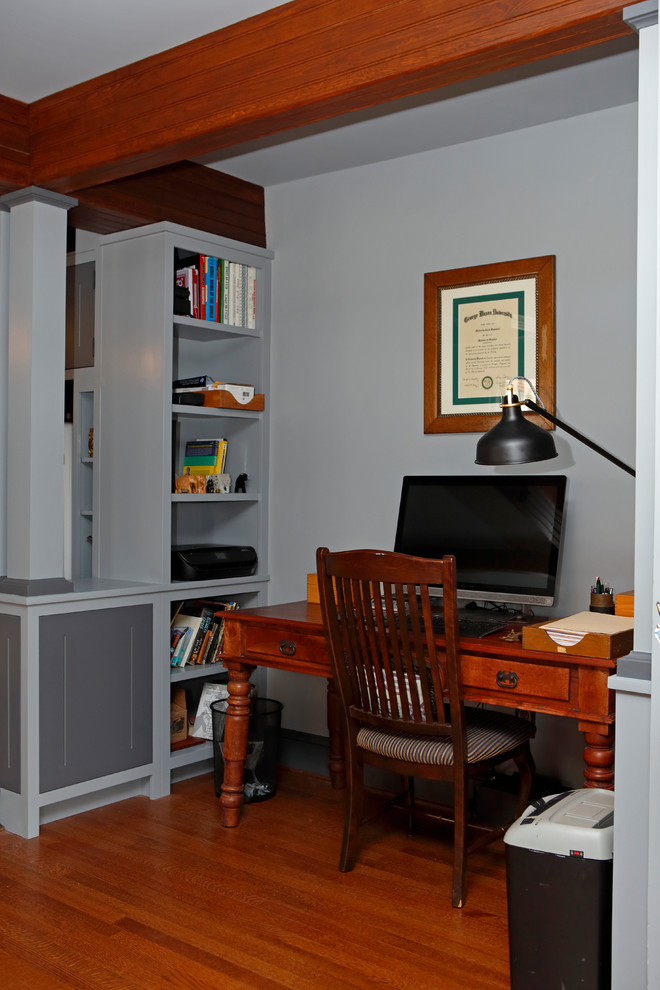 Inredning av ett eklektiskt litet arbetsrum, med grå väggar, mellanmörkt trägolv och ett fristående skrivbord