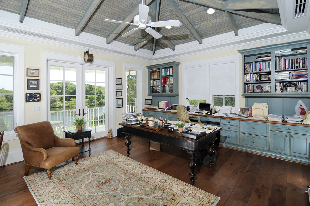 Imagen de despacho tradicional con paredes beige, suelo de madera oscura y escritorio independiente
