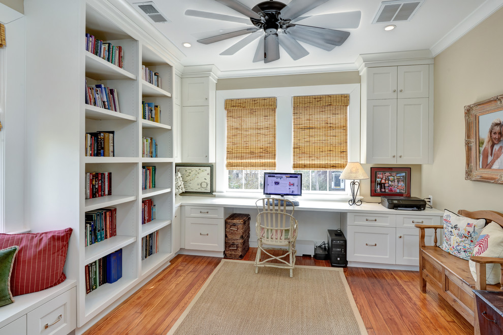 Klassisches Arbeitszimmer mit Arbeitsplatz, beiger Wandfarbe, braunem Holzboden und Einbau-Schreibtisch in Charleston