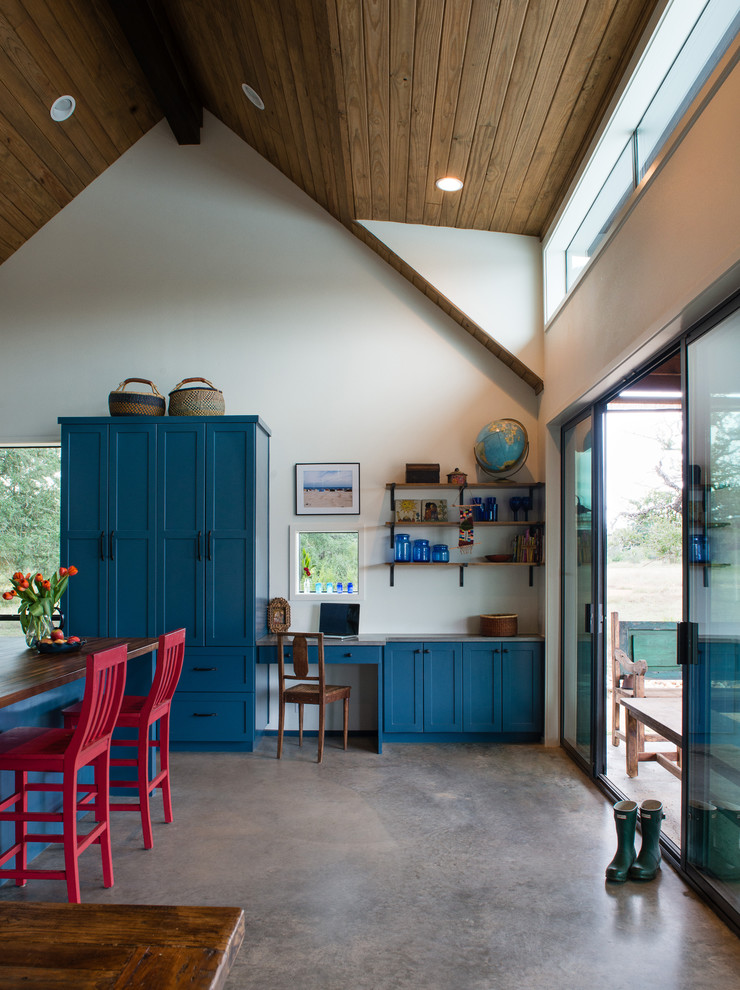 Foto de despacho de estilo de casa de campo pequeño sin chimenea con paredes blancas, suelo de cemento y escritorio empotrado