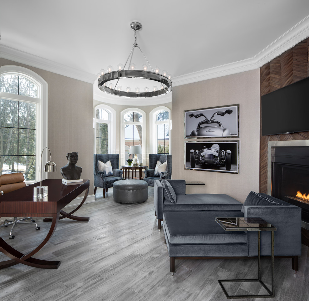 デトロイトにあるラグジュアリーな広いトランジショナルスタイルのおしゃれなホームオフィス・書斎 (標準型暖炉、木材の暖炉まわり、自立型机、ベージュの壁、淡色無垢フローリング、グレーの床) の写真