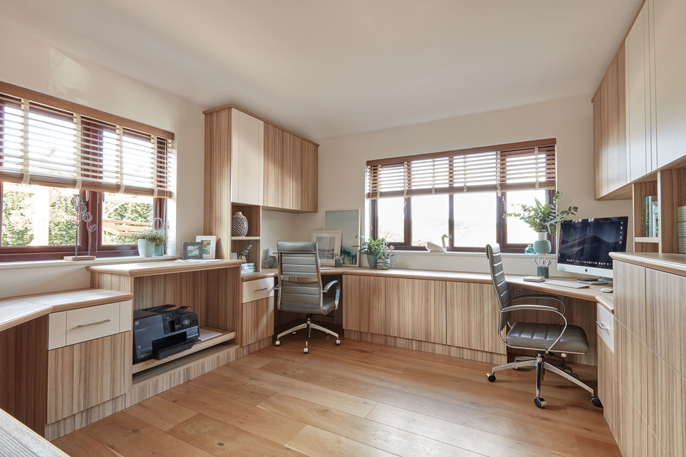 Photo of a medium sized contemporary home office in Manchester with beige walls, medium hardwood flooring, a built-in desk and brown floors.