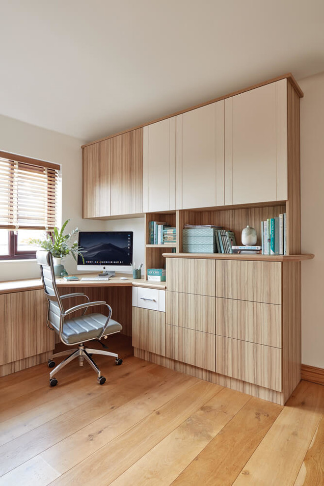 Photo of a medium sized contemporary home office in Manchester with beige walls, medium hardwood flooring, a built-in desk and brown floors.