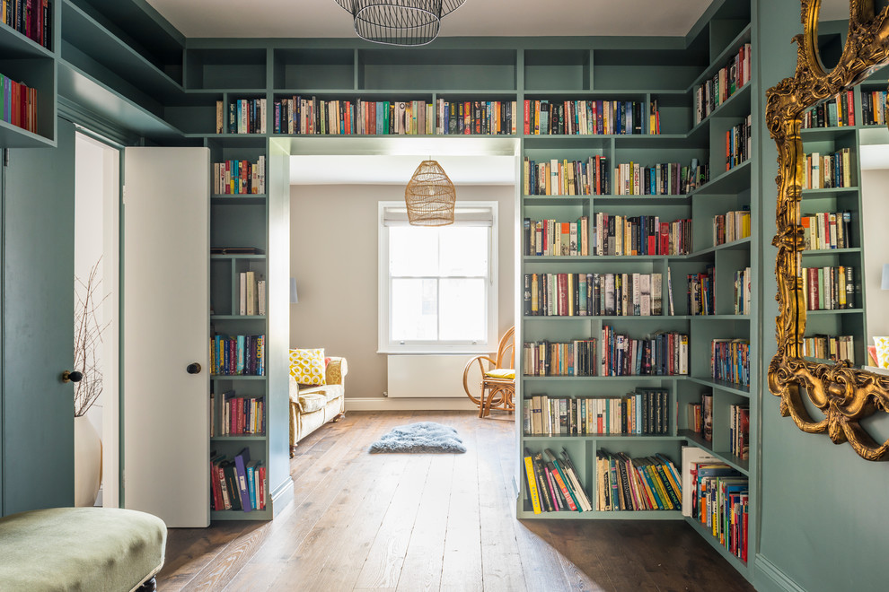 Exempel på ett mellanstort eklektiskt arbetsrum, med ett bibliotek, gröna väggar, mörkt trägolv och brunt golv