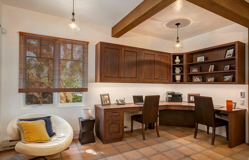 Photo of a large study in San Diego with white walls, terracotta flooring, no fireplace and a built-in desk.