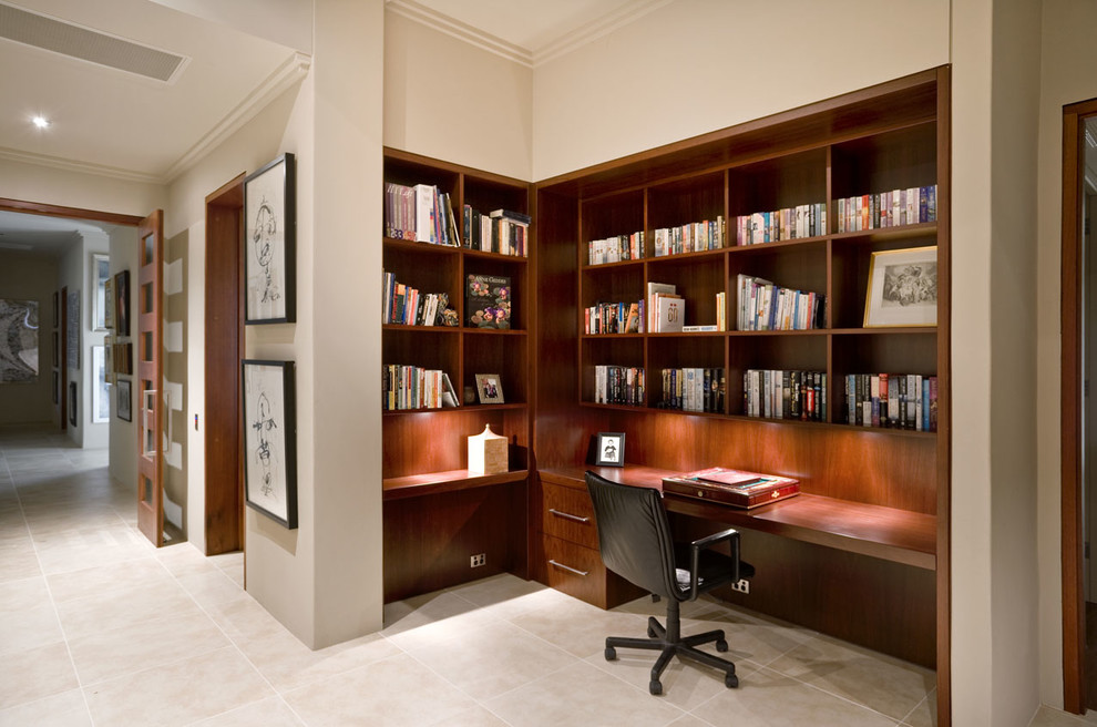 This is an example of a medium sized modern study in Sydney with beige walls, travertine flooring and a built-in desk.