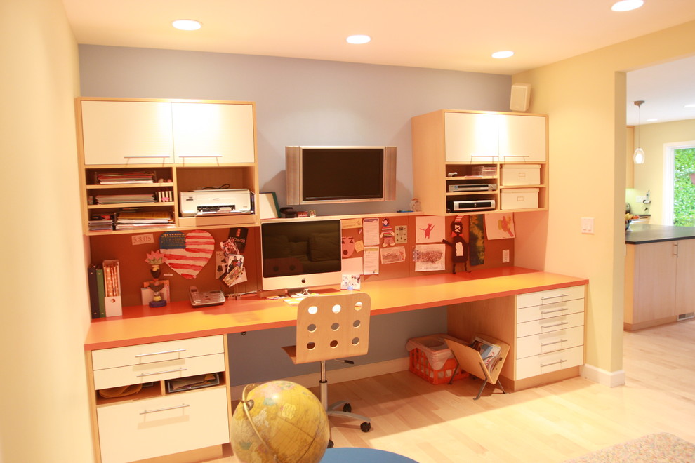 Modelo de despacho contemporáneo con paredes beige, suelo de madera en tonos medios y escritorio empotrado