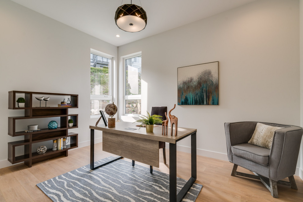 This is an example of a medium sized contemporary study in Vancouver with white walls, laminate floors, a freestanding desk and brown floors.
