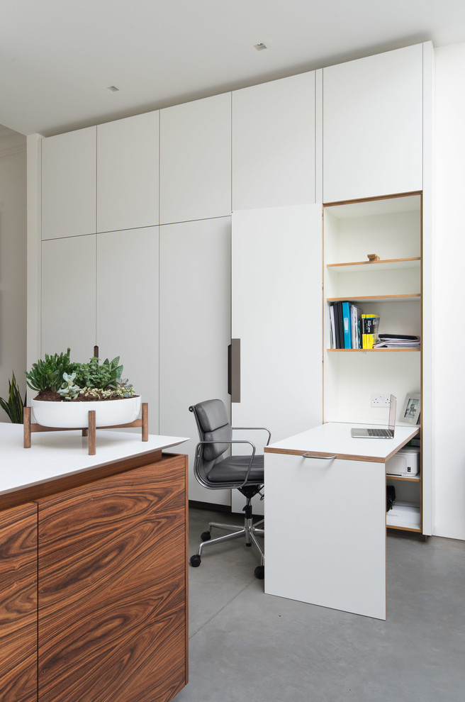 Idée de décoration pour un bureau design avec un mur blanc, sol en béton ciré et un bureau intégré.