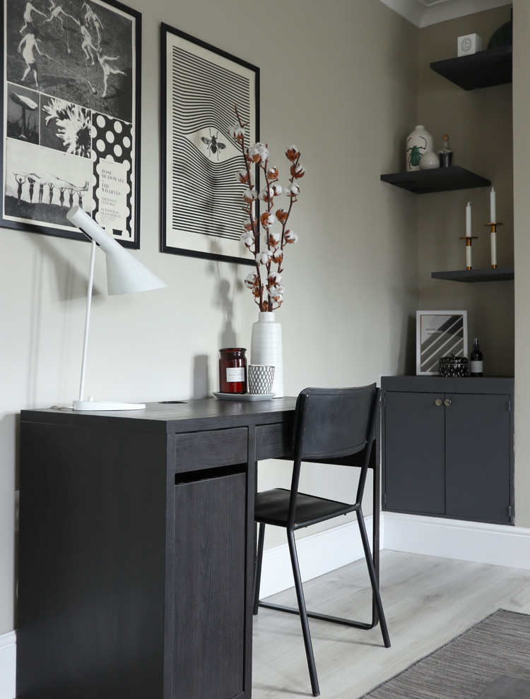 Inredning av ett modernt arbetsrum, med grå väggar, ljust trägolv, ett fristående skrivbord och grått golv