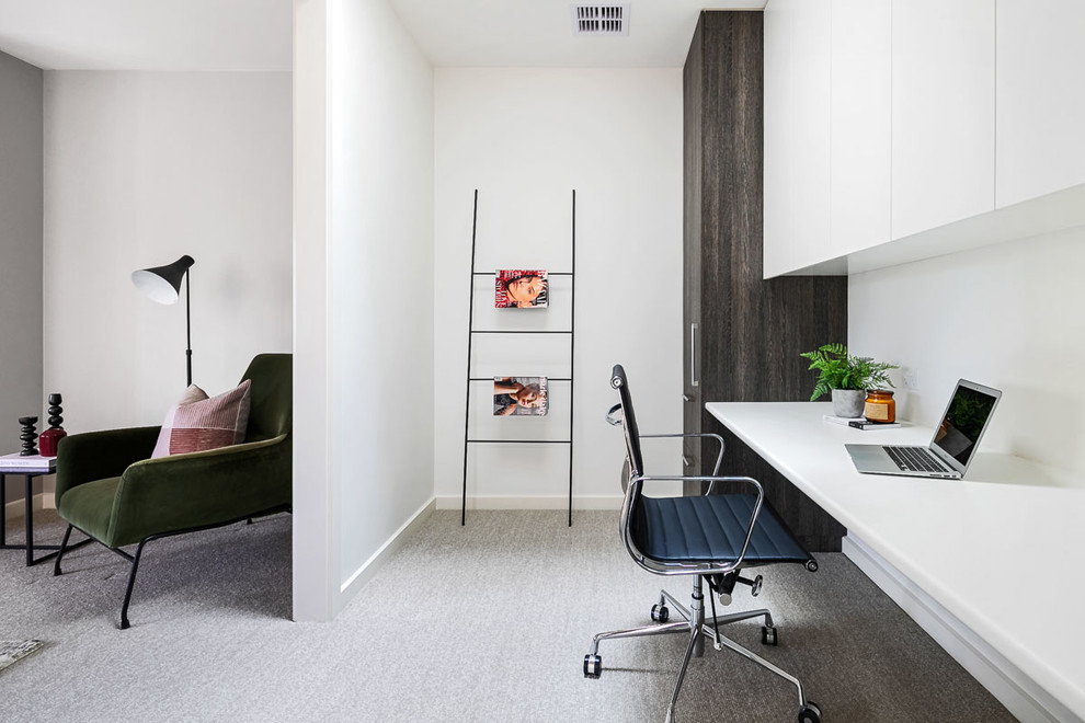 Modernes Arbeitszimmer mit weißer Wandfarbe, Teppichboden, Einbau-Schreibtisch und grauem Boden in Melbourne