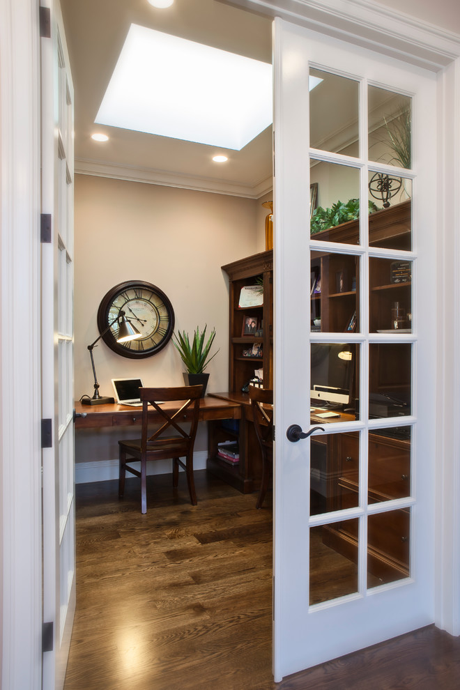 Kleines Klassisches Arbeitszimmer ohne Kamin mit beiger Wandfarbe, dunklem Holzboden, freistehendem Schreibtisch und braunem Boden in San Francisco
