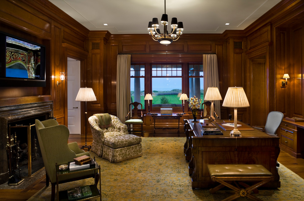 This is an example of an expansive classic study in Cleveland with brown walls, a freestanding desk and brown floors.