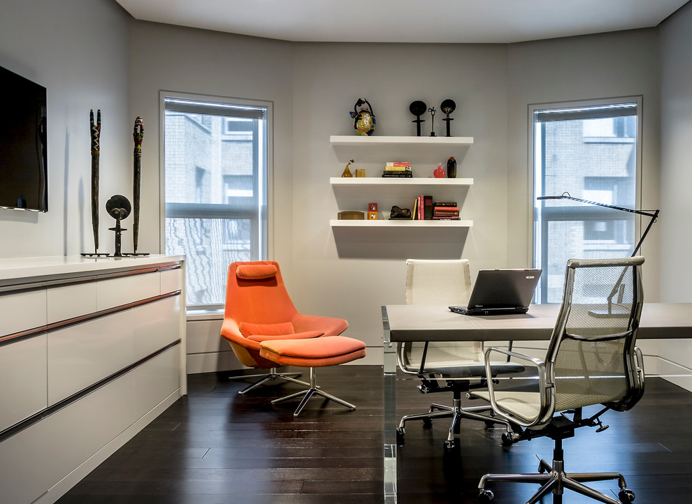 Modern inredning av ett arbetsrum, med grå väggar, mörkt trägolv och ett fristående skrivbord