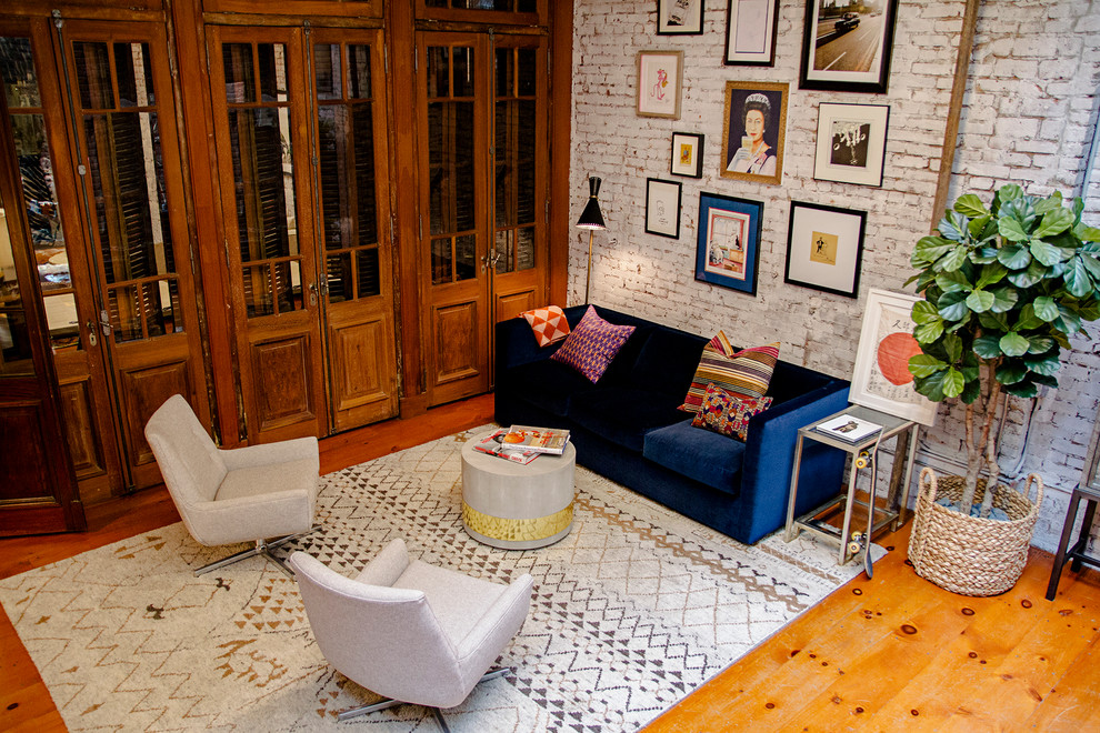 Bild på ett stort eklektiskt hemmabibliotek, med vita väggar, mellanmörkt trägolv, ett fristående skrivbord och brunt golv