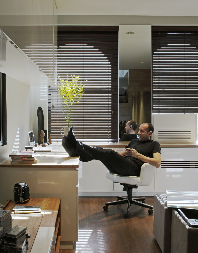 Modernes Arbeitszimmer mit weißer Wandfarbe, dunklem Holzboden und Einbau-Schreibtisch in New York