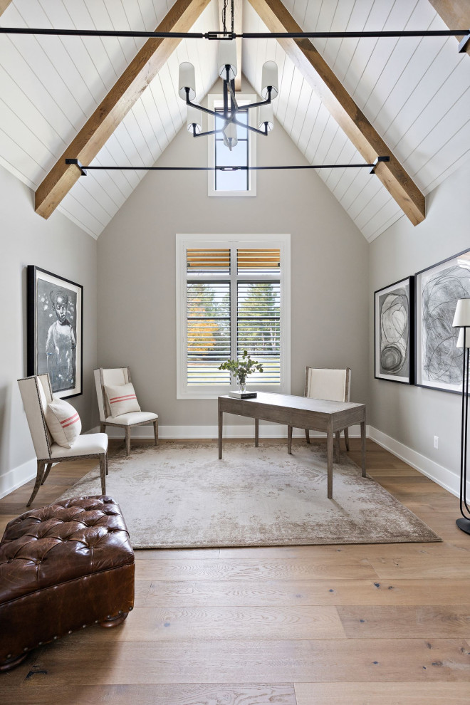 Aménagement d'un bureau campagne avec un mur gris, parquet clair, un bureau indépendant et poutres apparentes.