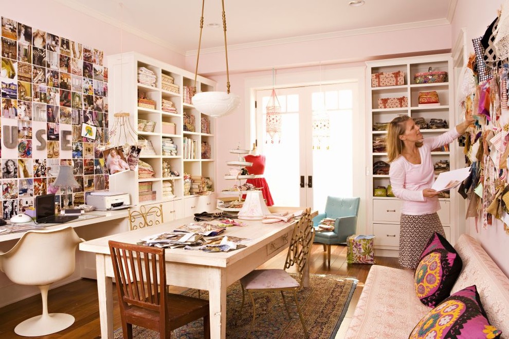 Diseño de estudio bohemio con paredes rosas, suelo de madera en tonos medios y escritorio empotrado